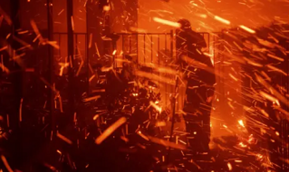 A man uses a garden hose to try to save his home from wildfire in Granada Hills, California, on 11 October 2019. Photograph: Michael Owen Baker/AP