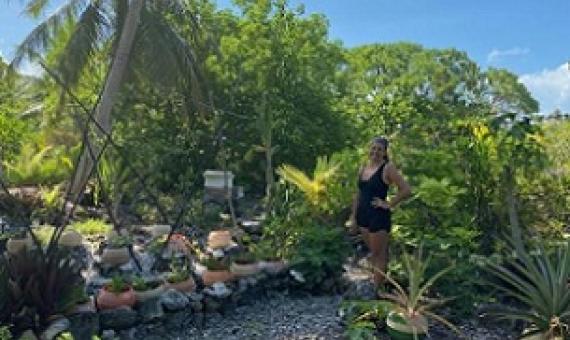 Kamoka Pearl co-owner Celeste Brash stands in front of a portion of the large garden that helps feed the farm crew. In soil made from bird droppings and coconut husks, they're attempting to grow everything from arugula and pineapples to taro and carrots in old broken buoys — all in an effort to be as self-sufficient as possible. Credit - Ashley Westerman/Courtesy The World