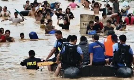 People wade in the chest deep floodwater in suburban Cainta, east of Manila, Philippines, in 2009. Such events will affect twice as many people by the end of the decade. Photograph: Pat Roque/AP
